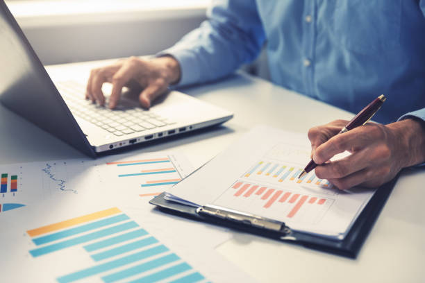 businessman analyzing annual business report with using laptop at office desk